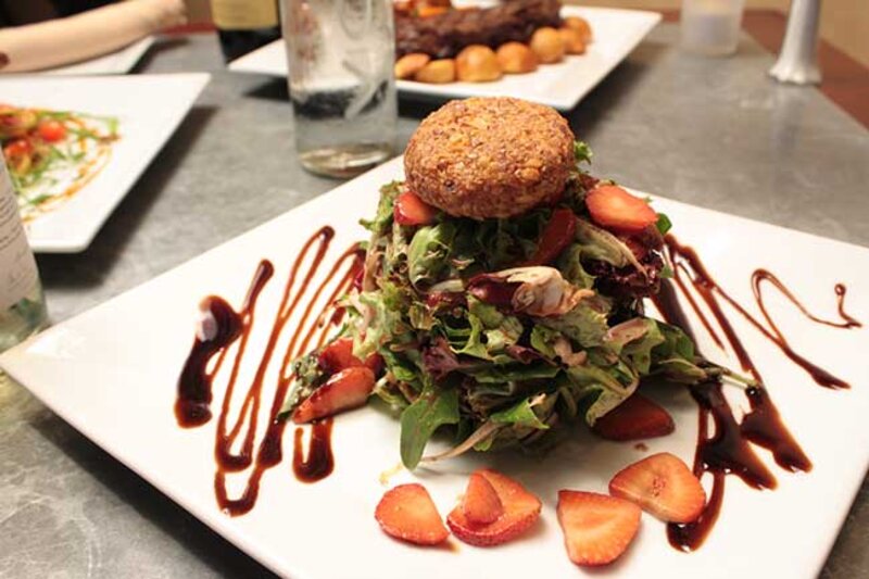 Salad topped with crab cake with balsamic dressing and strawberries