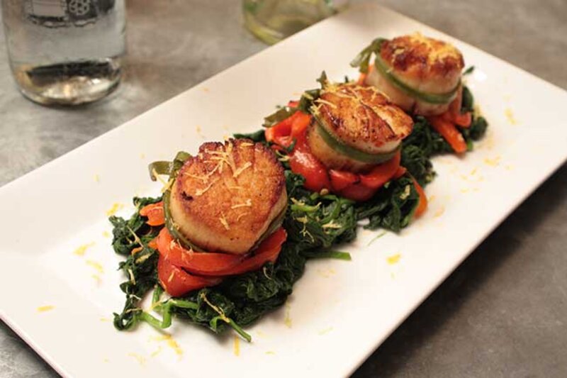 Scallops on a bed of roasted tomatoes and spinach